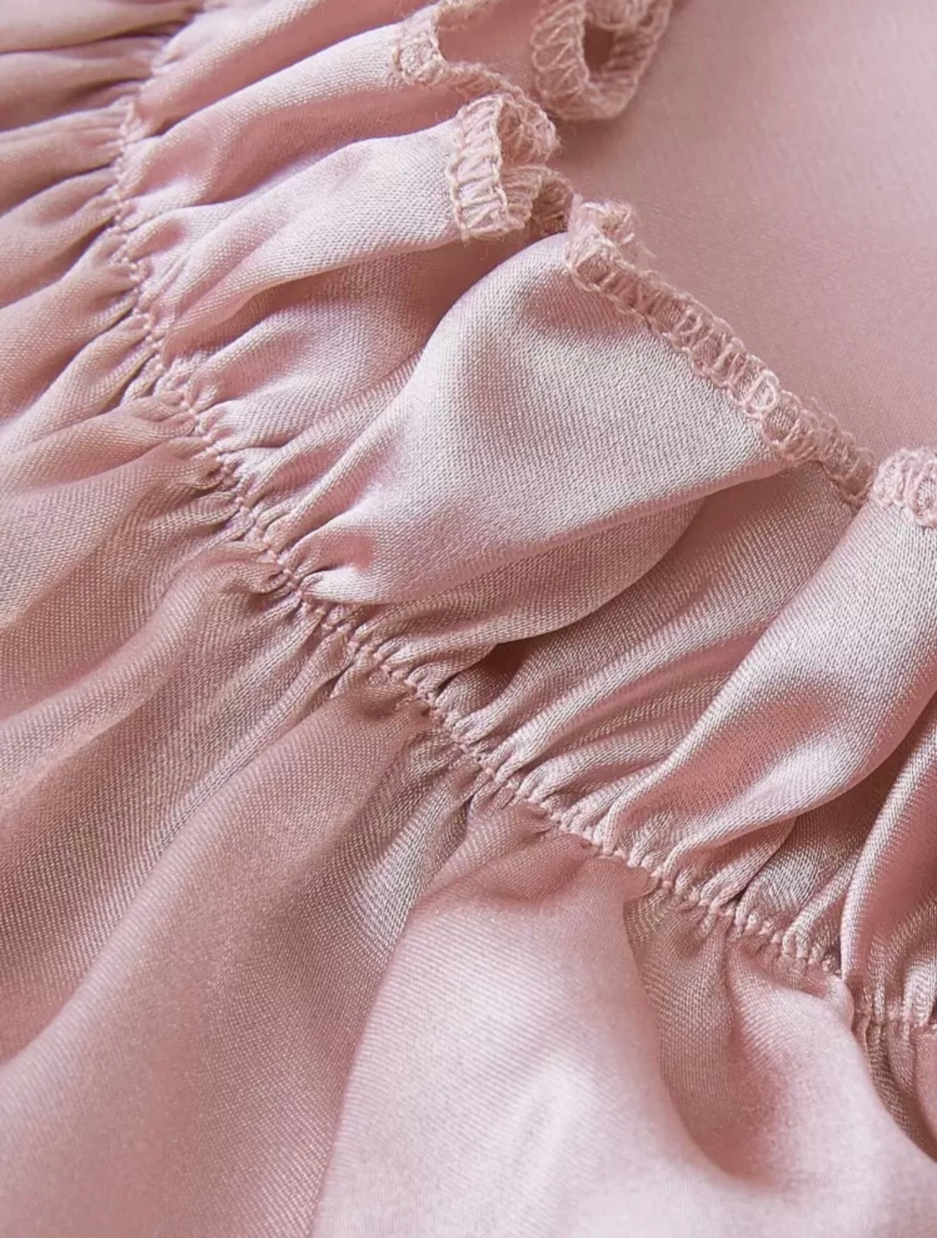 Gros plan sur les finitions et la texture soyeuse du bonnet de nuit rose poudré en soie de mûrier KAÏMINA.